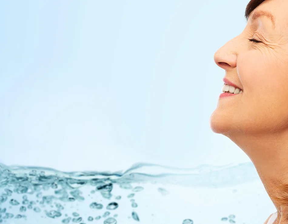Lächelnde Frau im Profil vor klarem Wasser und hellem Himmel